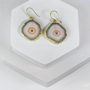 Sliced Quartz Earrings by Vanya Lara on a white display stand, part of a jewelry collection.