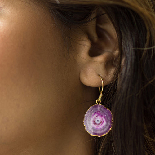 A close-up of a woman's ear wearing a Vanya Lara handcrafted purple sliced quartz earring.