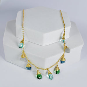 Kaleidoscope Drop Necklace by Vanya Lara with green hydro stones displayed on a white stand.