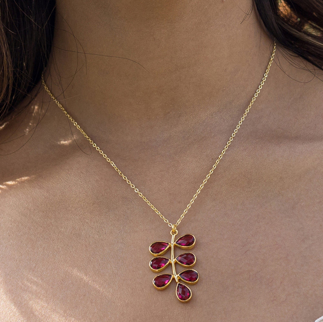 Woman wearing a Vanya Lara foliage necklace with a red hydro quartz pendant.