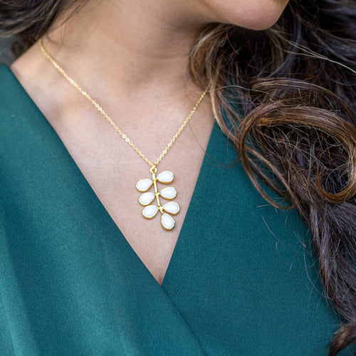 A woman showcasing a Foliage Necklace (VNK0004) by Vanya Lara, with a leaf-shaped pendant, highlighting an exquisite nature pattern.