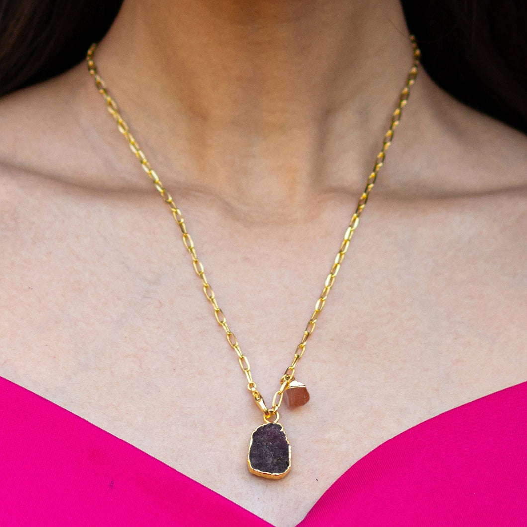 A woman wearing a pink top and a 22K gold-plated necklace with an Abstract Gemstone Pendant (VNK0005) from Vanya Lara.