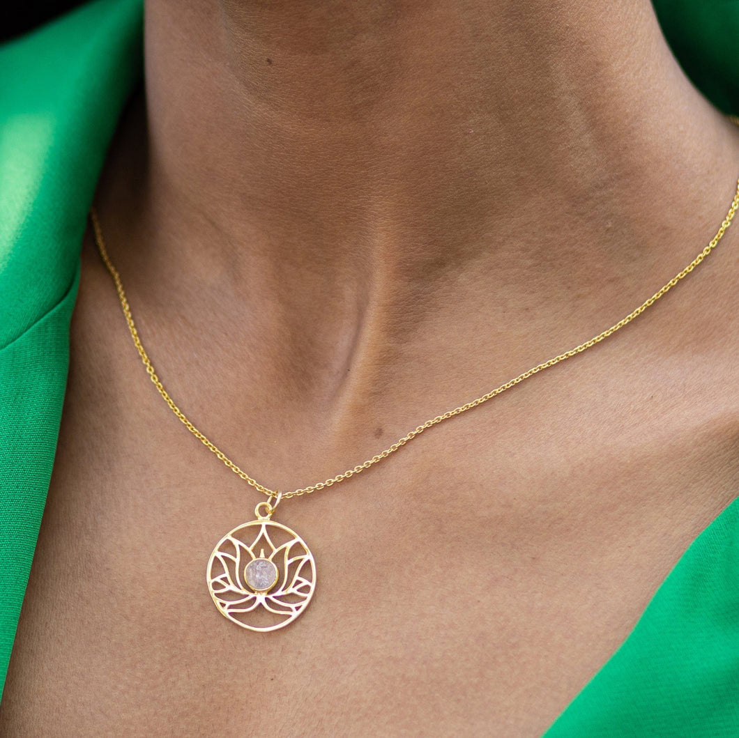 A delicate Golden Lotus Necklace - VNK0006 by Vanya Lara, with Lotus detail design worn on a person's neck against a green fabric background.