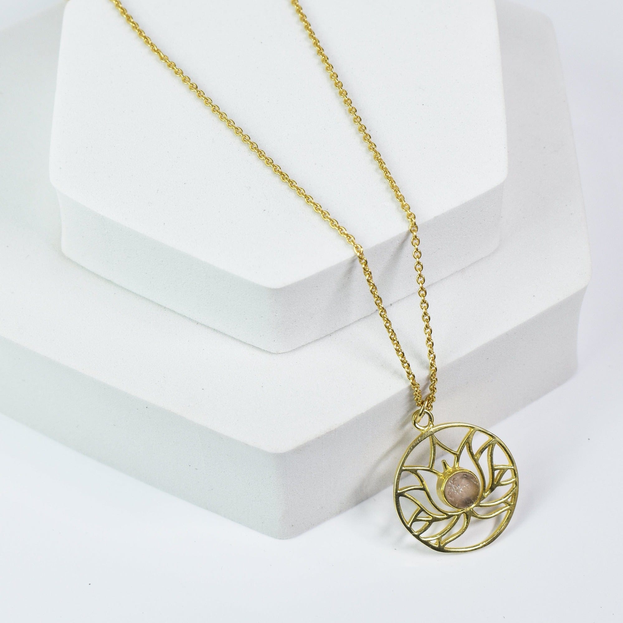 Golden Lotus Necklace by Vanya Lara with lotus detail design and gemstones on a white display stand.