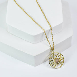 Golden Lotus Necklace by Vanya Lara with lotus detail design and gemstones on a white display stand.