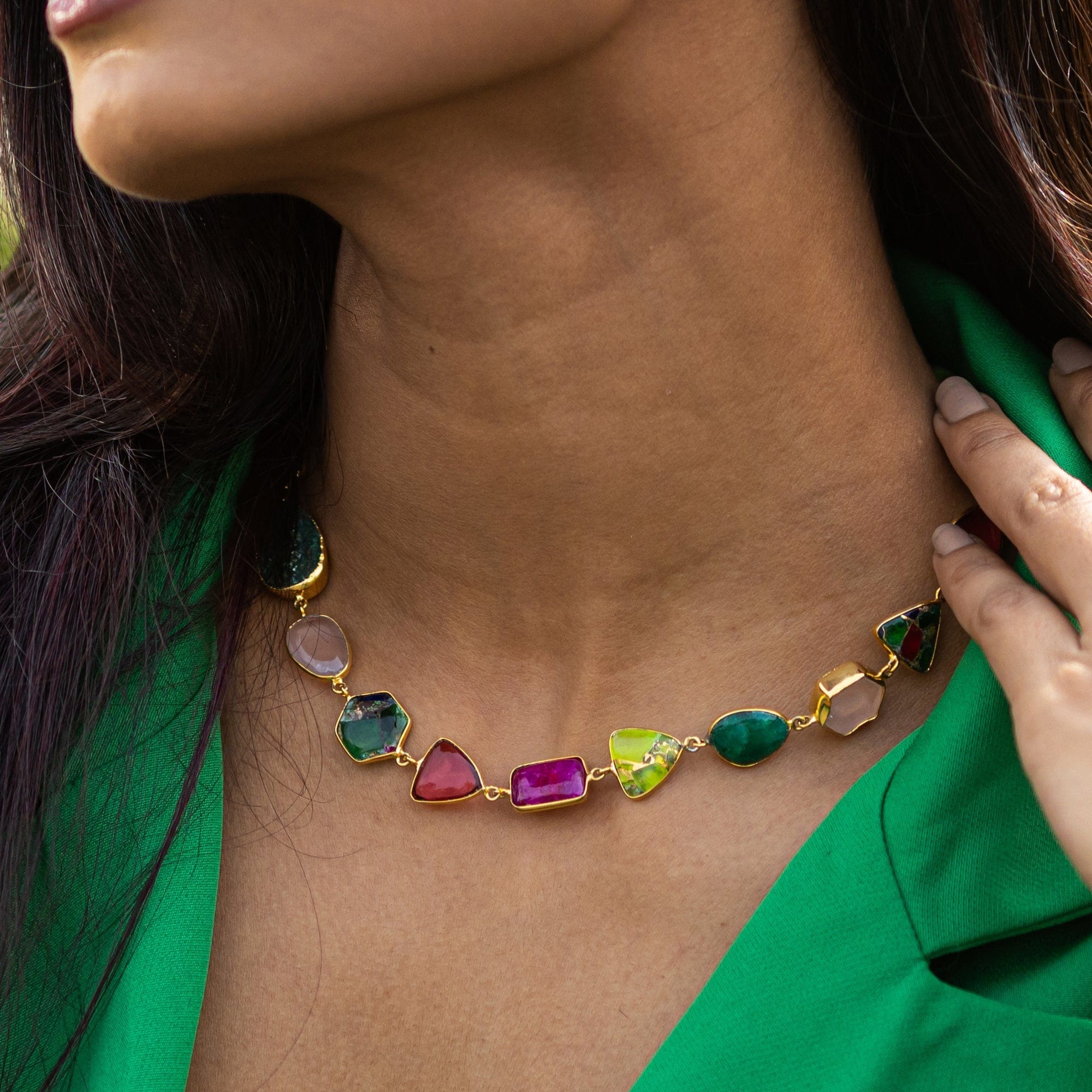 A woman showcasing an Enchanting Melody Necklace by Vanya Lara against a green blouse.