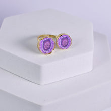 Load image into Gallery viewer, A ring with dual purple geode stones set in gold, displayed on a white pedestal, now part of our exclusive Solar Quartz Ring - VRG0001 collection by Vanya Lara.
