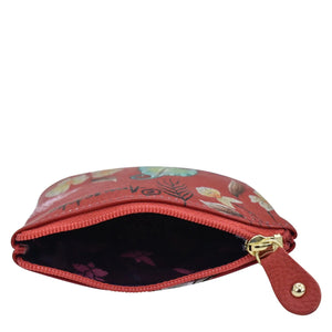 A small, open red leather Anuschka cosmetic bag with a floral pattern and a gold-colored zipper.