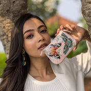 A woman showcasing a decorated leather Medium Zip Pouch - 1107 by Anuschka.
