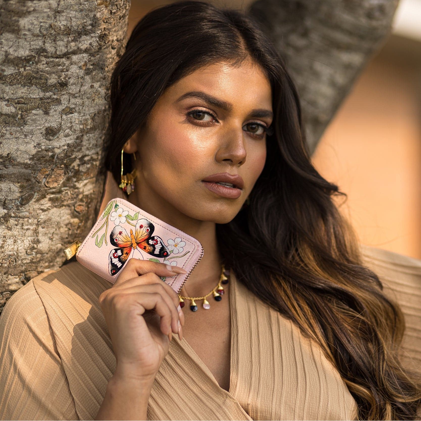 A woman posing with Anuschka's Accordion Style Credit And Business Card Holder - 1110 by a tree.