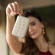 A woman holding a small, Anuschka Accordion Style Credit And Business Card Holder - 1110 up to the camera, her face slightly blurred in the background.