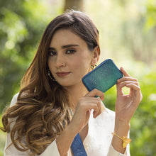 Load image into Gallery viewer, Woman holding up a small blue Anuschka Accordion Style Credit And Business Card Holder - 1110 outdoors.
