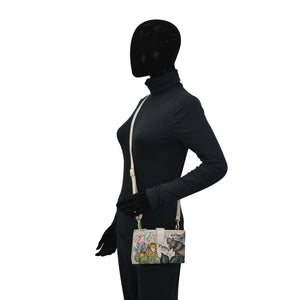 Mannequin with a black face cover wearing a dark outfit and holding an Anuschka Cell Phone Case & Wallet - 1113.