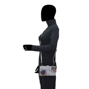 Woman in a gray top and black pants carrying a Anuschka genuine leather floral white handbag.