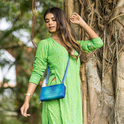 Woman in green traditional dress standing by a tree with an Anuschka Organizer Wallet Crossbody - 1149 featuring RFID protection.