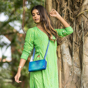 Woman in green traditional dress standing by a tree with an Anuschka Organizer Wallet Crossbody - 1149 featuring RFID protection.