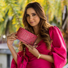 Load image into Gallery viewer, Woman holding a chic red Three Fold Wallet - 1150 clutch by Anuschka with palm trees in the background.

