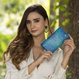 Woman holding a blue leather Three Fold Wallet - 1150 with RFID protection outdoors by Anuschka.