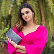 Woman in a pink dress holding a gray Anuschka Three Fold Wallet - 1150 clutch bag.