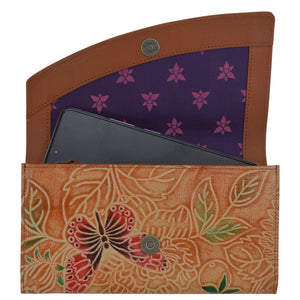 A smartphone inside an Anuschka Accordion Flap Wallet - 1174 with floral embossed genuine leather and purple patterned lining with RFID protection.