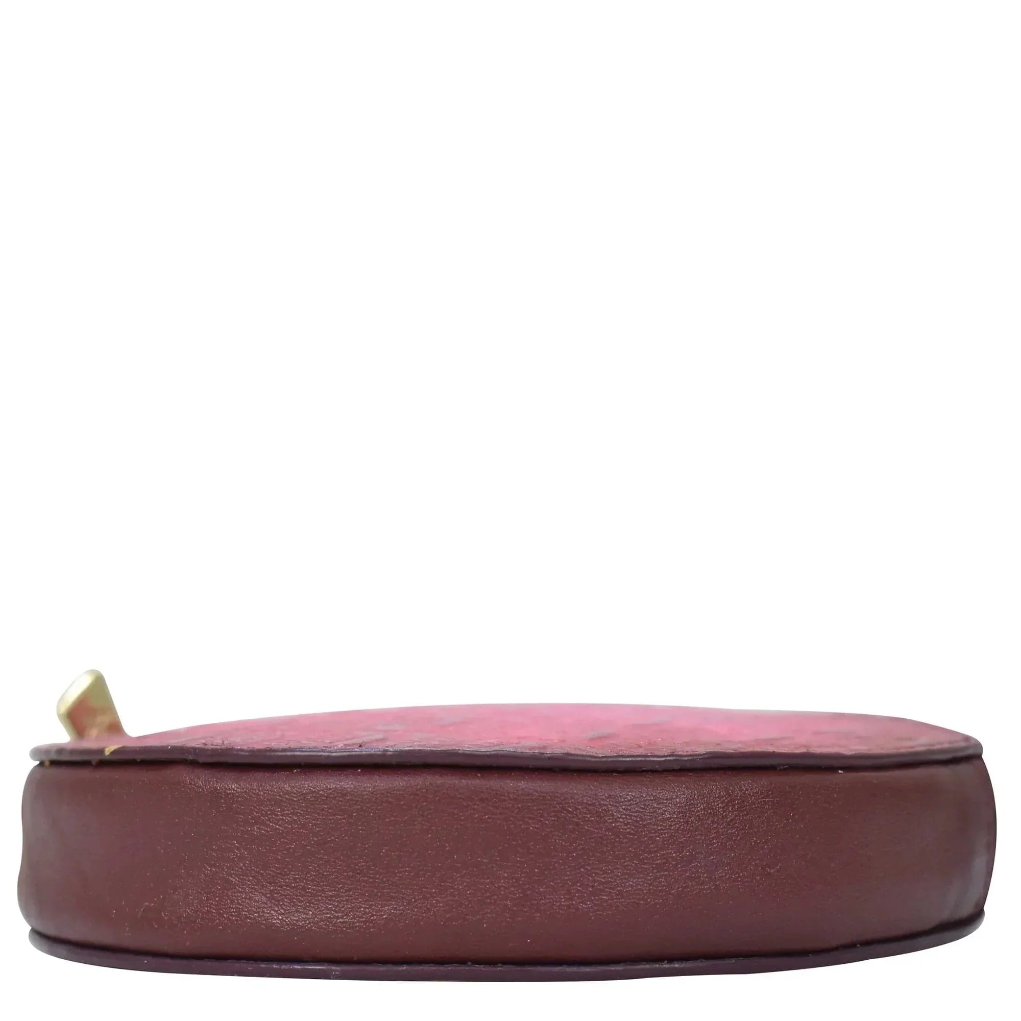 A side view of an empty, Anuschka Round Coin Purse - 1175 in genuine leather maroon on a white background.