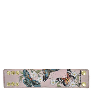 Genuine leather pale pink Anuschka wrist band with hand-painted butterfly print and gold-tone snap fasteners.