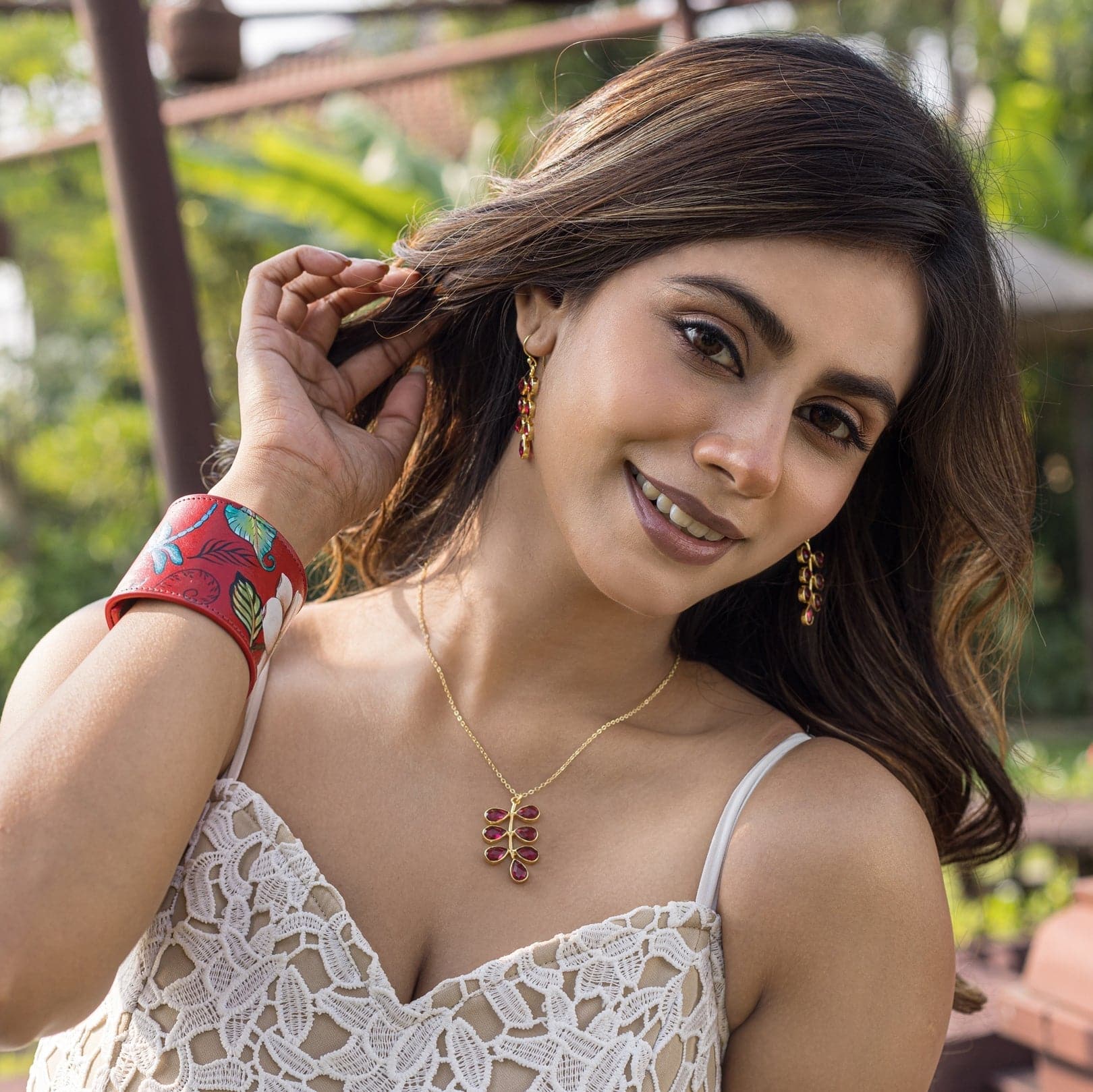 Woman smiling outdoors while adjusting her Anuschka hand-painted earring.