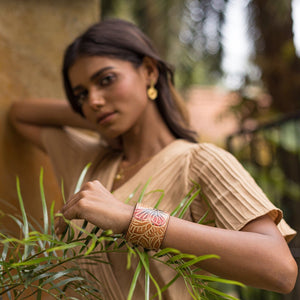 Woman in a beige dress posing with a focus on her traditionally designed, hand-painted Anuschka Leather Adjustable Leather Wrist Band - 1176.