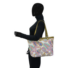 Load image into Gallery viewer, Mannequin with black bodysuit holding a Anuschka Fabric with Leather Trim Zip Top City Tote - 12005.
