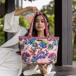 A woman showcasing a colorful floral Anuschka Fabric with Leather Trim Zip Top City Tote - 12005.