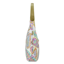Load image into Gallery viewer, Side view of a white paisley-patterned Anuschka sling bag with green shoulder strap and zippered pockets.
