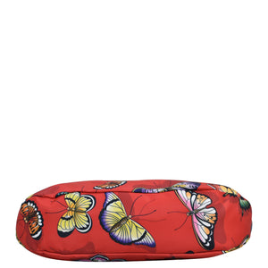 A red cylindrical bolster with a colorful butterfly pattern and zippered pockets, Anuschka's Fabric with Leather Trim Large Sling Hobo - 12010.