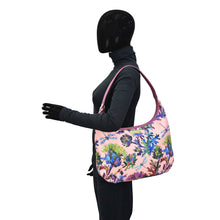 Load image into Gallery viewer, Mannequin wearing a black bodysuit and gloves showcasing a floral pink Fabric with Leather Trim Large Sling Hobo - 12010 from Anuschka with zippered pockets.
