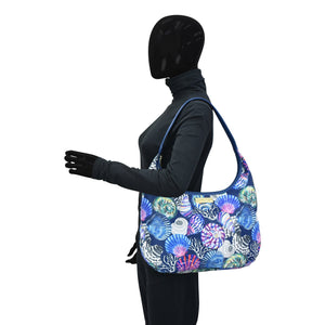 A person in a black bodysuit with Anuschka's Fabric with Leather Trim Large Sling Hobo - 12010, featuring a zippered pocket, posed against a white background.