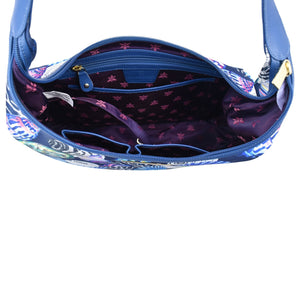 An overhead view of an open, empty Anuschka Fabric with Leather Trim Large Sling Hobo - 12010 handbag with a star-patterned interior lining and a zippered pocket.