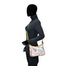 Load image into Gallery viewer, Person wearing a full-body suit and gloves, carrying an Anuschka Fabric with Leather Trim East/West Hobo - 12013 with an adjustable handle drop.
