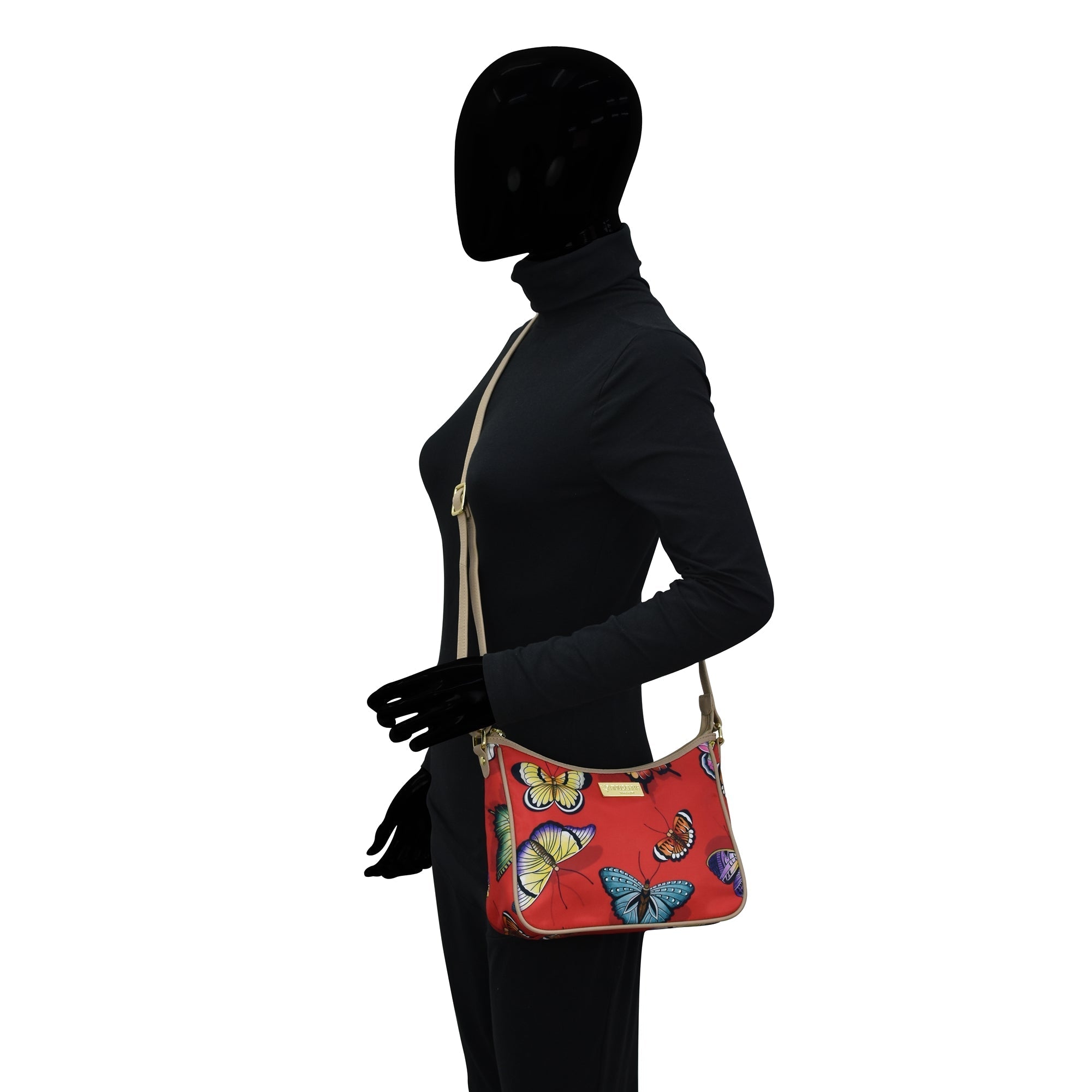 Mannequin wearing a black outfit and gloves showcasing an Anuschka Fabric with Leather Trim East/West Hobo - 12013 with an adjustable handle drop.