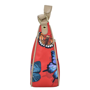 Side view of a colorful butterfly-print Fabric with Leather Trim East/West Hobo - 12013 wristlet bag by Anuschka with an adjustable handle drop.