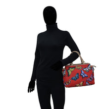 Load image into Gallery viewer, Mannequin wearing a black bodysuit and gloves, holding an Anuschka Fabric with Leather Trim Multi Compartment Satchel - 12014 with an adjustable strap.
