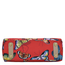 Load image into Gallery viewer, An Anuschka red clutch with a colorful butterfly print, gold-tone hardware accents, and a zippered compartment.
