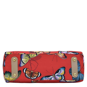 An Anuschka red clutch with a colorful butterfly print, gold-tone hardware accents, and a zippered compartment.
