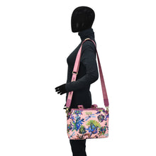 Load image into Gallery viewer, A mannequin wearing a black sweater and pants accessorized with an Anuschka Fabric with Leather Trim Multi Compartment Satchel - 12014 in pink floral design, featuring an adjustable strap and matching shoulder strap.
