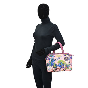 Mannequin in a black bodysuit holding an Anuschka Fabric with Leather Trim Multi Compartment Satchel - 12014 with an adjustable strap.