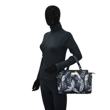 Load image into Gallery viewer, Mannequin in a black outfit holding an Anuschka Fabric with Leather Trim Multi Compartment Satchel - 12014 handbag with a tropical design, featuring an adjustable strap.
