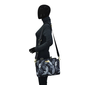 Sentence with replaced product: Mannequin with black head displaying a Anuschka Fabric with Leather Trim Multi Compartment Satchel - 12014 with an adjustable strap.