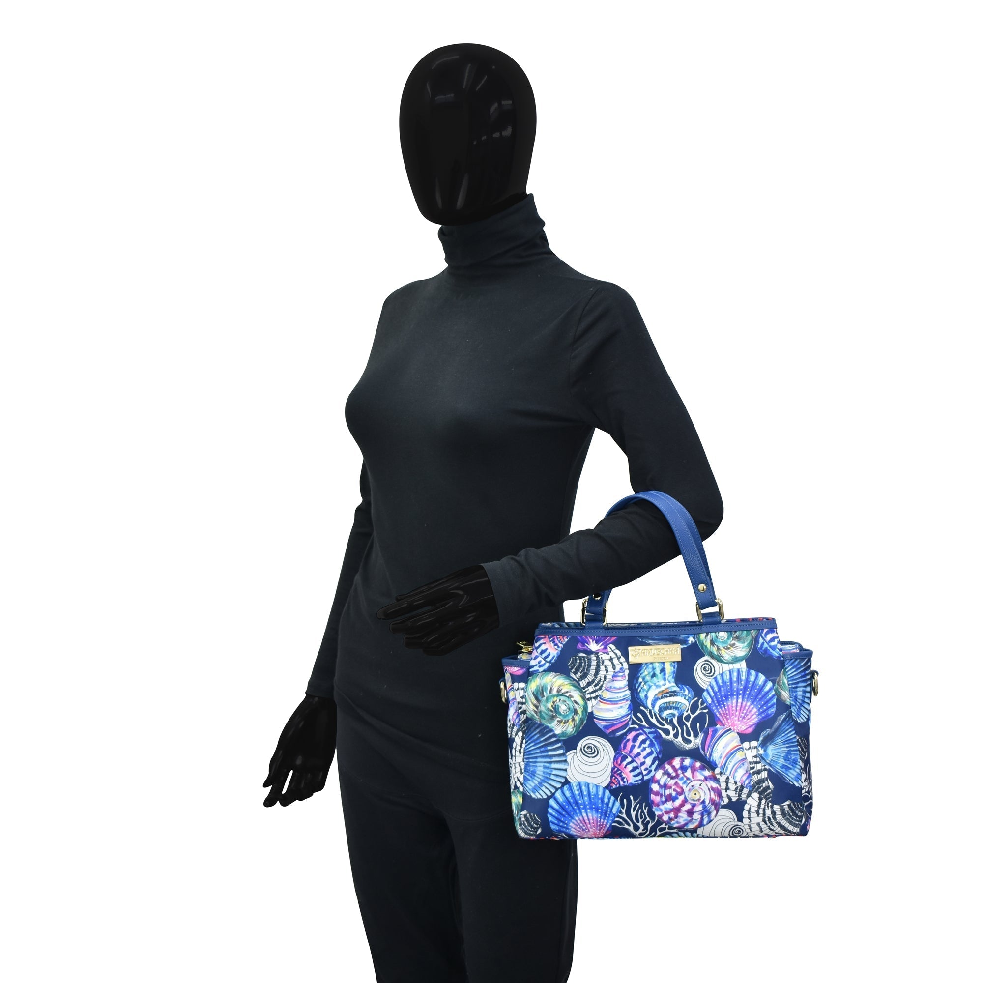 Mannequin in a black bodysuit holding an Anuschka Fabric with Leather Trim Multi Compartment Satchel - 12014 with an adjustable strap.