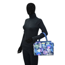 Load image into Gallery viewer, Mannequin in a black bodysuit holding an Anuschka Fabric with Leather Trim Multi Compartment Satchel - 12014 with an adjustable strap.
