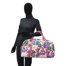 Load image into Gallery viewer, Mannequin dressed in a black full-body garment holding a pink floral Anuschka Fabric with Leather Trim Great Escape Duffle - 12016 with a zippered pocket.
