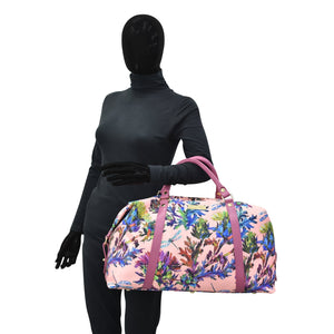 Mannequin dressed in a black full-body garment holding a pink floral Anuschka Fabric with Leather Trim Great Escape Duffle - 12016 with a zippered pocket.
