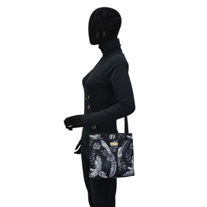 Mannequin displaying an Anuschka Fabric with Leather Trim Crossbody with Slip Pocket - 12017 shoulder bag with a tropical print design and rear zippered pockets.